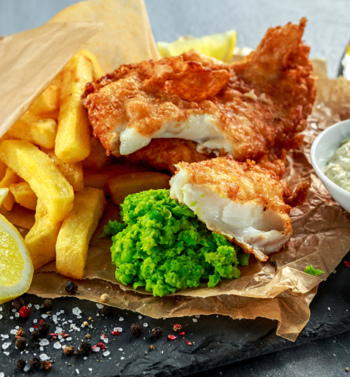fresh plate of fried cod and chips with mashed peas
