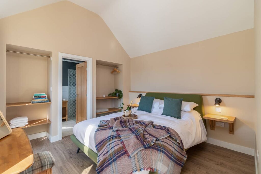 Sheep Shed master bedroom with large, cozy bed and view to en-suite bathroom