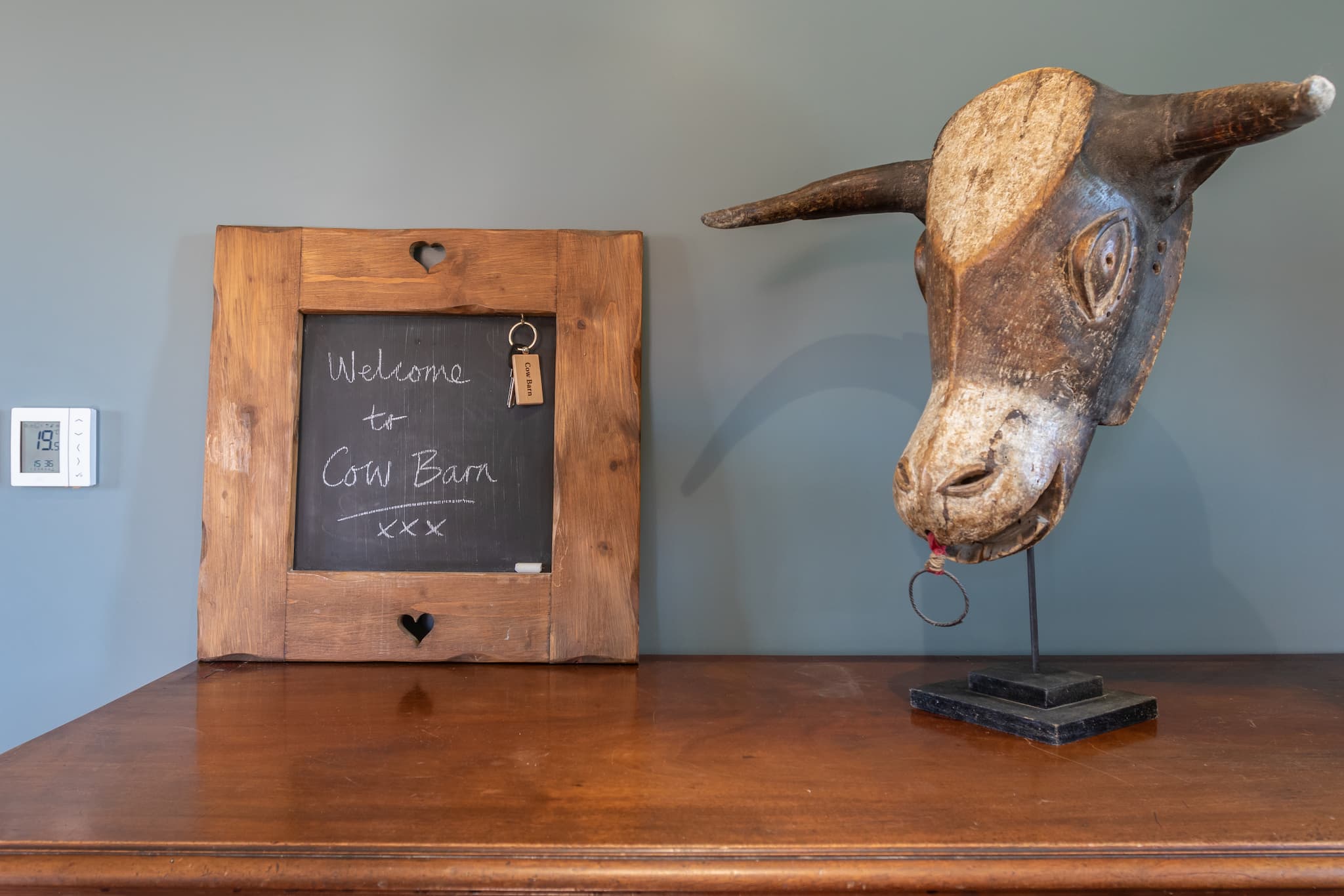 chalkboard sign reads "welcome to cow barn", next to a how head sculpture